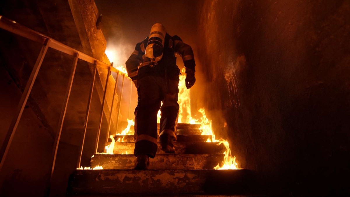 tűzoltó fut egy lépcsőn körülötte tűz