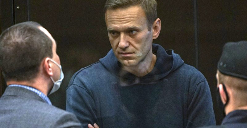 Alekszej Navalnij sötét pulóverben néz az előtérben kettő ember