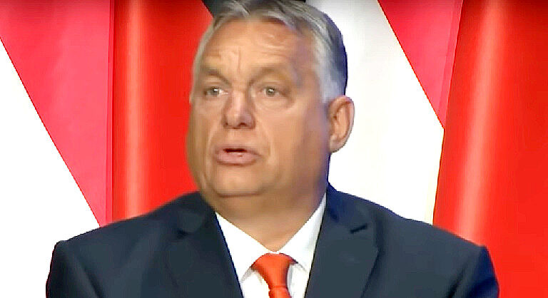 Orbán Viktor fekete zakóban, fehér ingben, narancssárga nyakkendőben, balra fordulva ijedten beszél.