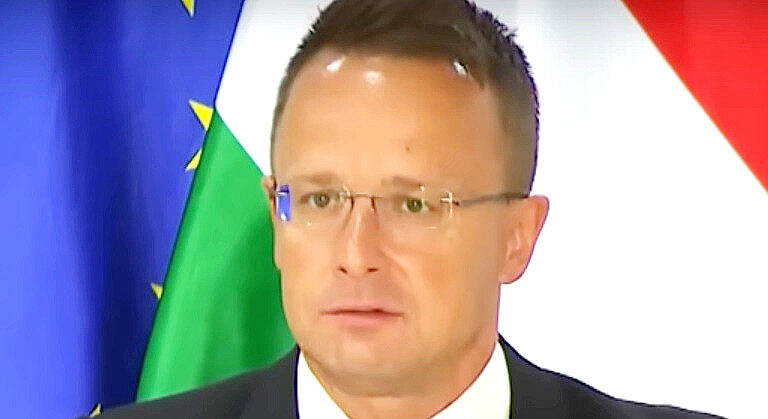 Szijjártó Péter szemüvegben, rövid hajjal, zakóban, fehér ingben ijedten néz.