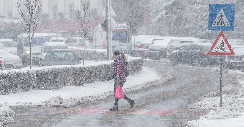 Havazás közben az utcán átsétáló nő látszik a képen.