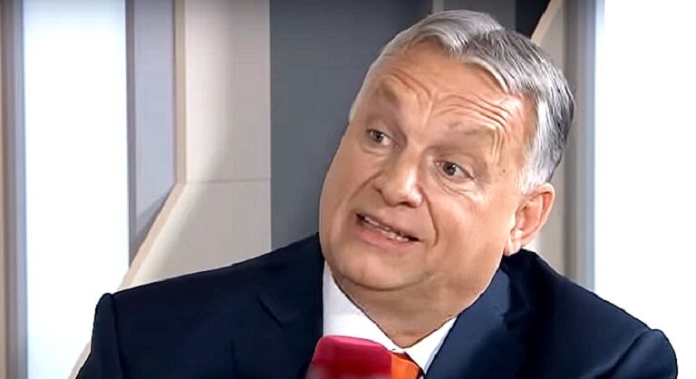 Orbán Viktor fekete zakóban, fehér ingben, ősz hajjal, ráncos homlokkal, jobbra döntött fejjel beszél, miközben balra néz.