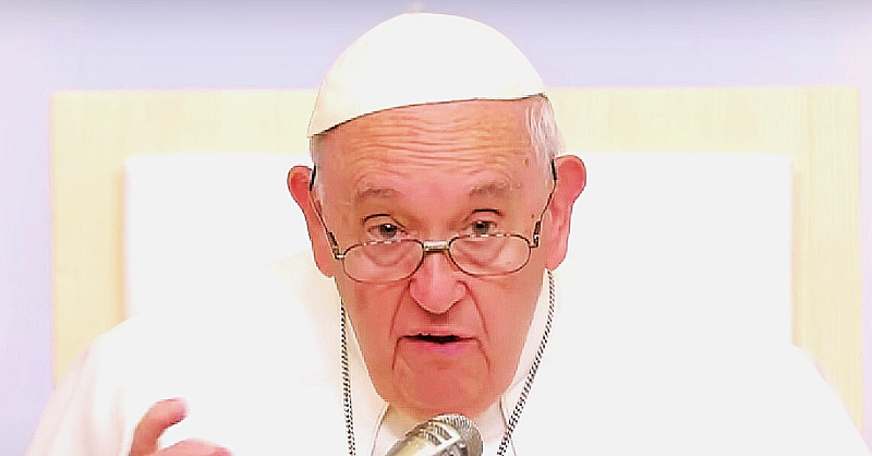 Ferenc pápa fehré fejfedpben, szemüvegben, ráncos homlokkal beszél a mikrofonba.