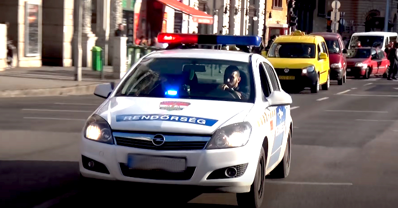 A képen egy szirénázó, fehér színű Opel Astra-rendőrautó látható.