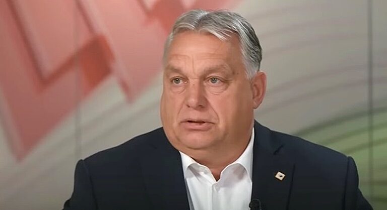 Orbán Viktor magyar miniszterelnök sötétzakóban és fehér ingben ül és beszél