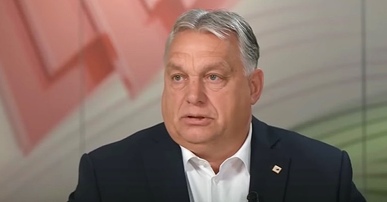 Orbán Viktor magyar miniszterelnök sötétzakóban és fehér ingben ül és beszél