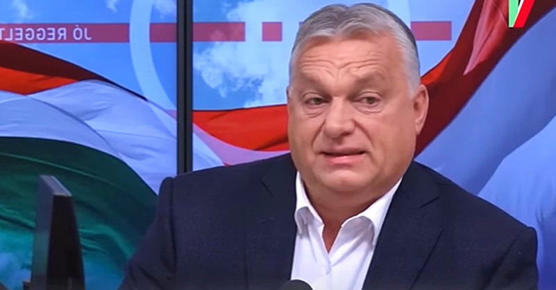 Orbán Viktor fehér ingben, fekete öltönyben egy mikrofon előtt beszél