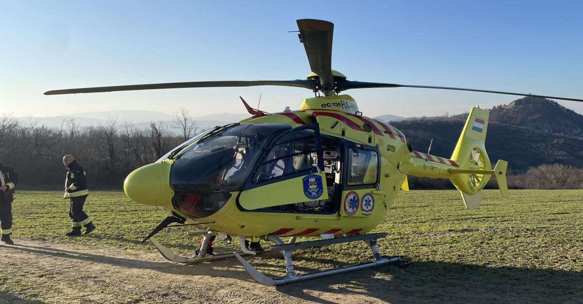 Az Országos Mentőszolgálat citromsárga színű mentőhelikoptere látható a képen egy pusztaságban.