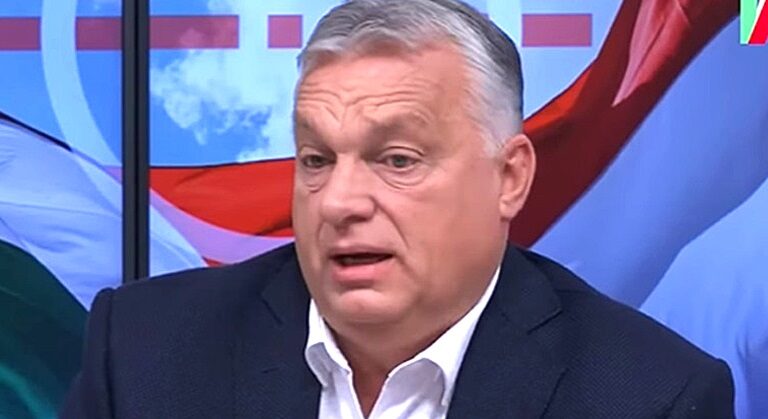 Orbán Viktor színes háttér előtt sötét öltönyben beszél