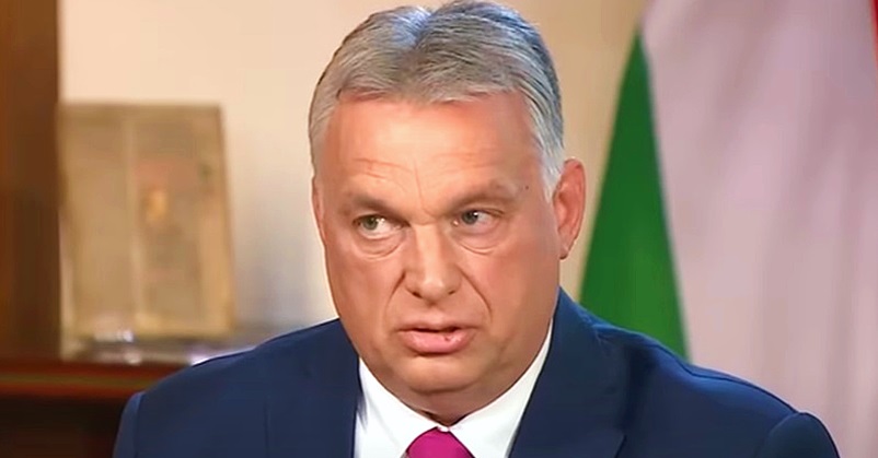 Orbán Viktor kék zakóban, fehér ingben és vörös nyakkendőben látható, amint furcsán grimaszol.