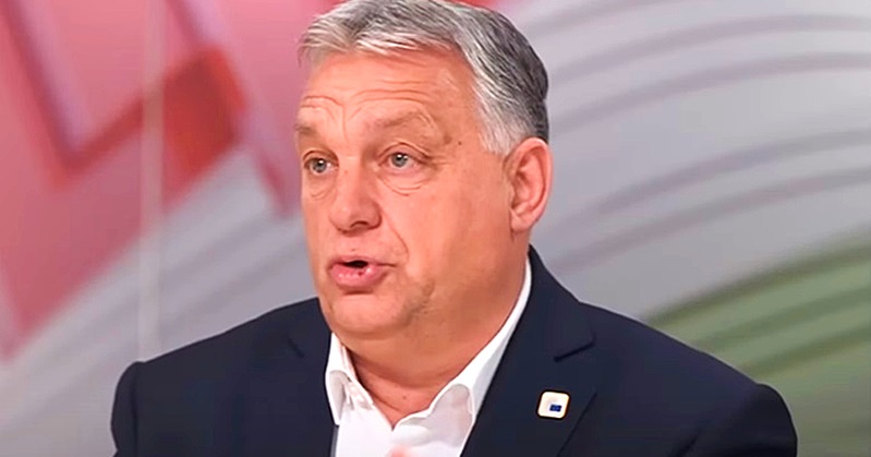 Orbán Viktor kék zakóban, fehér ingben, kitűzőben, ősz hajjal meglepetten néz oldalra.