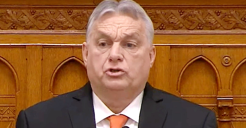 Orbán Viktor a parlamentben beszél ráncos, meggyötört fejjel, fekete zakóban, fehér ingben és narancssárga nyakkendőben.