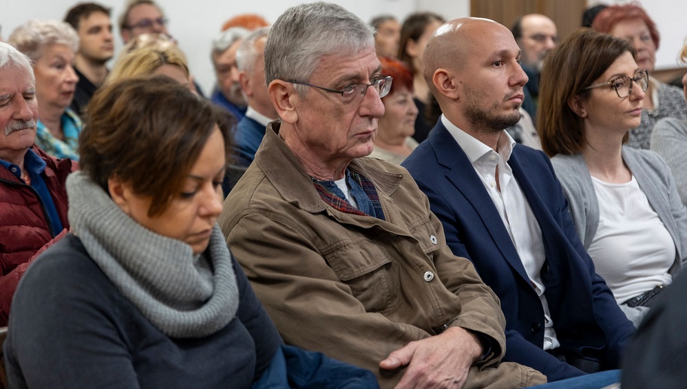 A képen Gyurcsány Ferenc, a Demokratikus Koalíció elnök-frakcióvezetője barna kabátban és szemüvegben átható, mellette jobbra Rónai Sándor, a DK EP-képviselője ül kék zakóban.