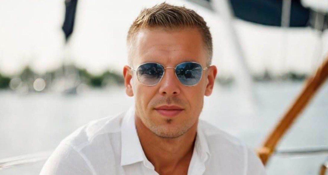 Magyar Péter fehér ingben napszemüvegben ül egy hajón a háttérben víz