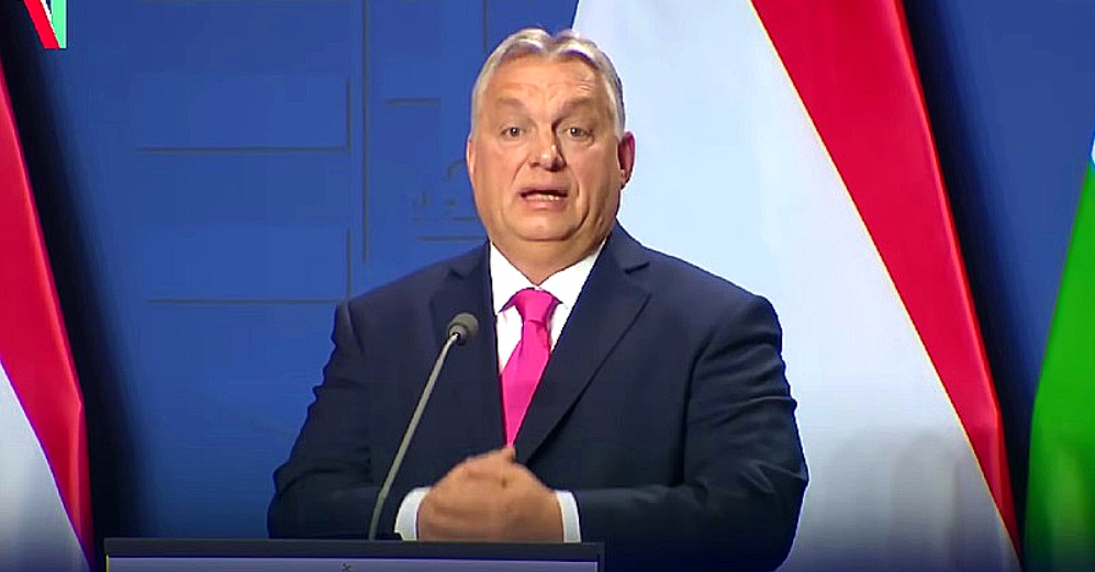 Orbán Viktor sötét öltönyben magenta nyakkendővel tátott szájjal beszél a mikrofonba