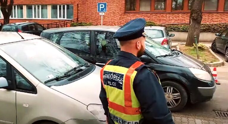 Rendőr Kónya Endre koccanásos eseténél, egyenruhában, szürke és fekete autók mellett intézkedik