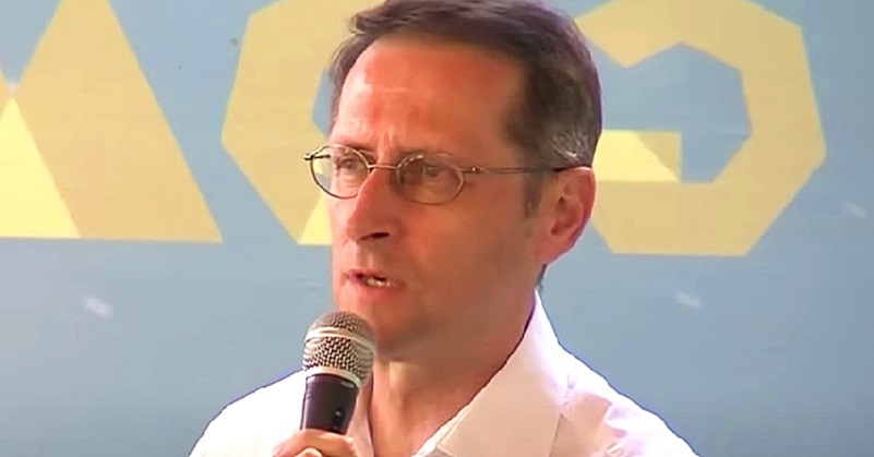 Varga Mihály fehér ingben mikrofonba beszél.