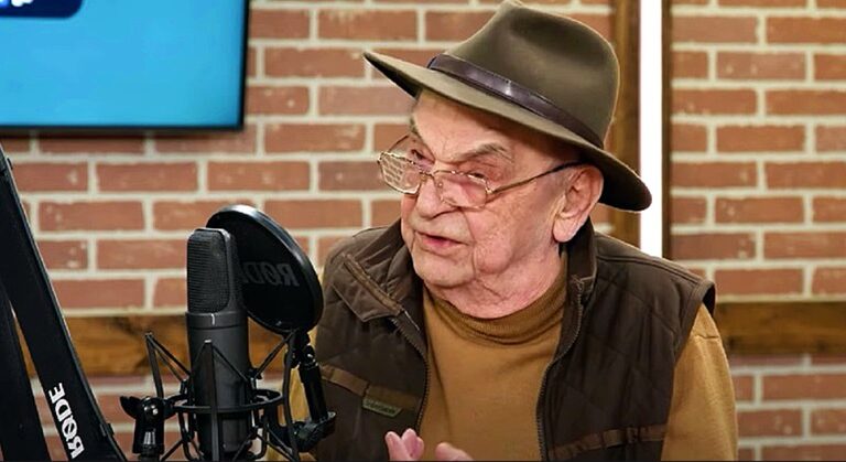 Bodrogi Gyula interjút adott, barna pulóverben, barna mellényben, barna kalapban a mikrofonba beszél