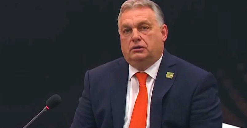 Orbán Viktor fekete háttér előtt, sötétkék öltönyben, narancssárga nyakkendőben