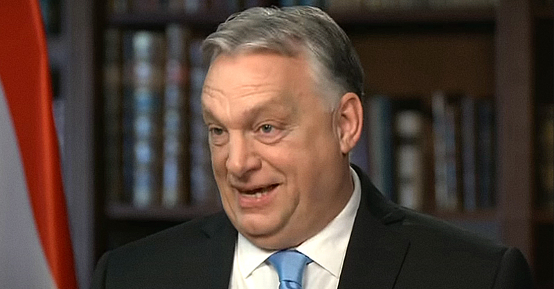 Orbán Viktor fekete zakóban, fehér ingben, kék nyakkendőben, ősz hajjal furcsán néz a kamerába.