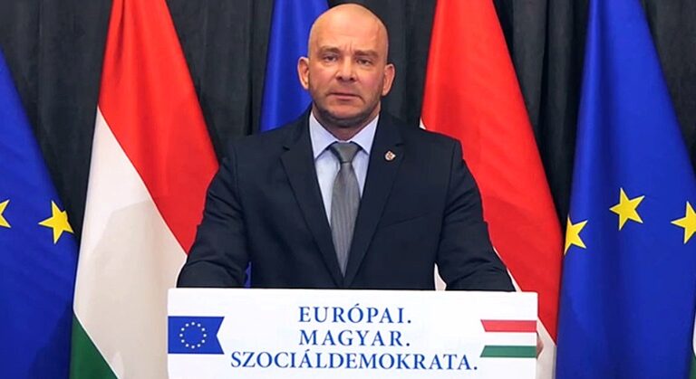 Mustó Géza, magyar zászló, EU-s zászló, fekete öltöny, kék ing, lila nyakkendő