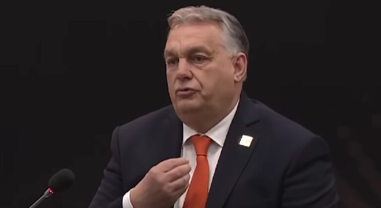 Orbán Viktor, fekete öltöny, fehér ing, narancssárga nyakkendő, fekete háttér