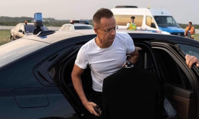 Szijjártó Péter külgazdasági és külügyminiszter száll ki a fekete luxus BMW-ből fehér izompolóban