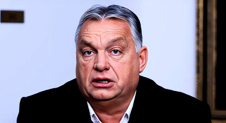 Orbán Viktor fekete zakóban, fehér ingben, meglepett tekintettel, rövid hajjal a kamerába néz.