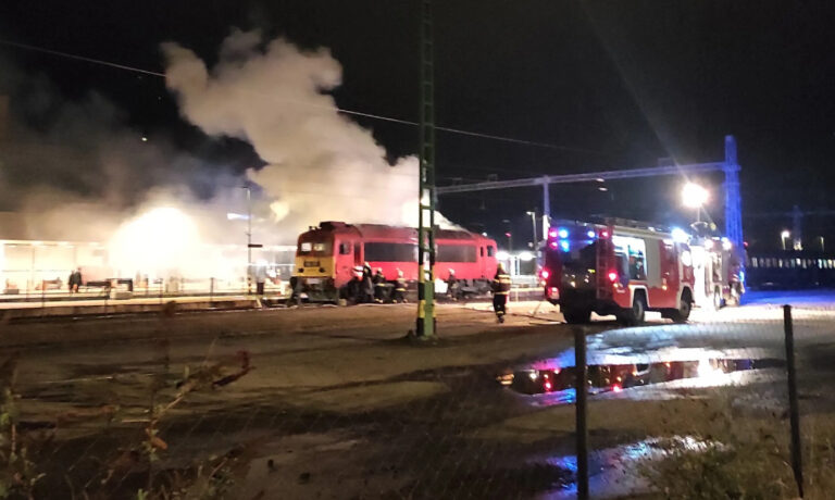 Kigyulladt MÁV vonat sötétben Tapolcán, egy tűzoltóatuó az előtérben