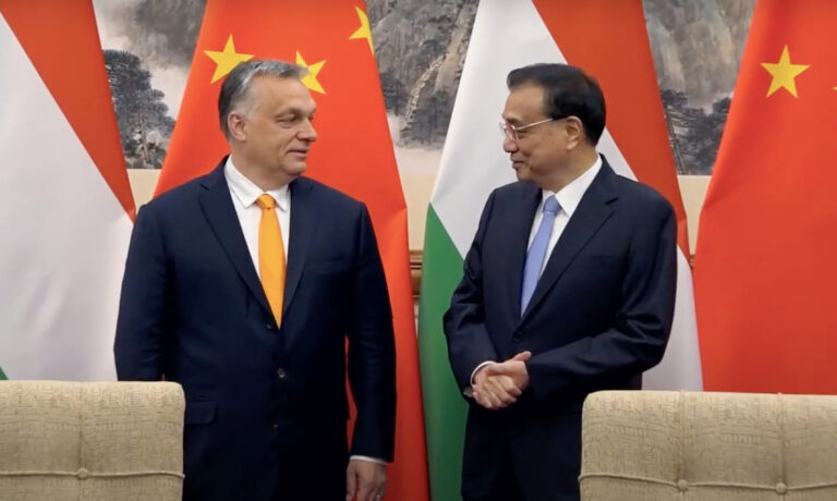 Orbán Viktor és Li Ko-csiang kínai miniszterelnök magyar és kínai zászlók előtt egymásra néz