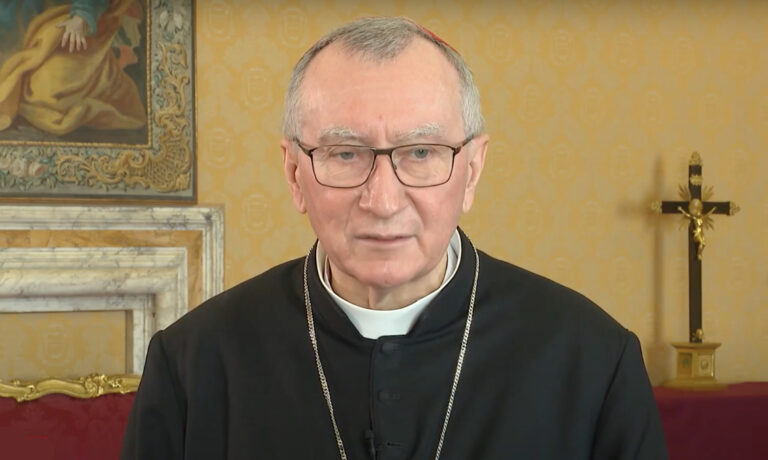 Pietro Parolin bíborosi öltözetben egy sárga fal, feszület és egy kép előtt