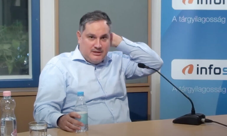 Nagy Márton világoskék ingben a fejét vakarja az Inforádió studiójában