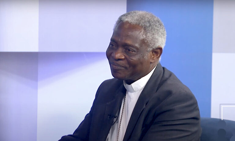 Peter Turkson beszél egy stúdióban egy sötétkék fotelen ülve