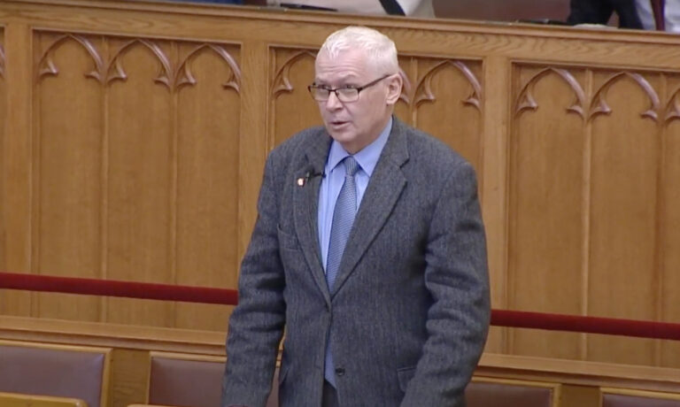 Polt Péter az Országgyűlésben beszél szürke zakóban