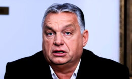 Orbán Viktor fekete zakóban, fehér ingben, meglepett tekintettel, rövid hajjal a kamerába néz.