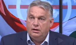 Orbán Viktor sötétkék zakóba, világoskék ingben, ősz hajjal, barna arccal, ősz hajjal balra néz a stúdióban.