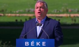 Orbán Viktor kék zakóban, kék ingben és kék pódium előtt.
