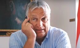 Orbán Viktor világoskék ingben, irodában, tollal a kezében