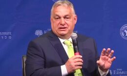 Orbán Viktor, mikrofon, kék háttér, fekete öltöny, fehér ing, zöld nyakkendő
